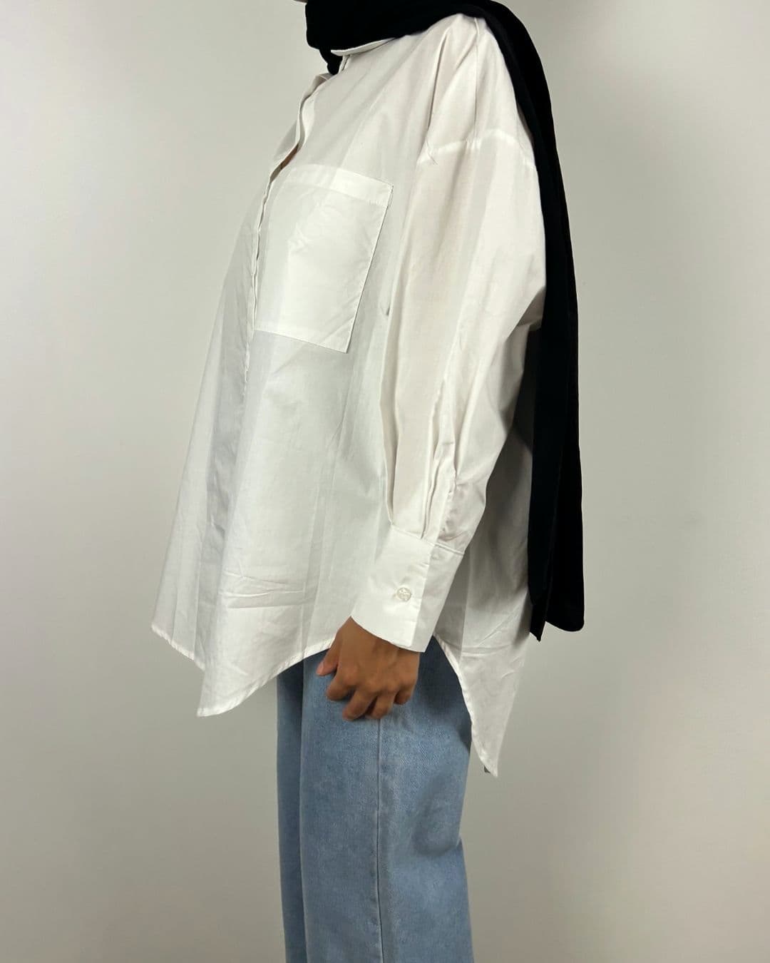 Profil gauche de la chemise oversize blanche portée avec jean