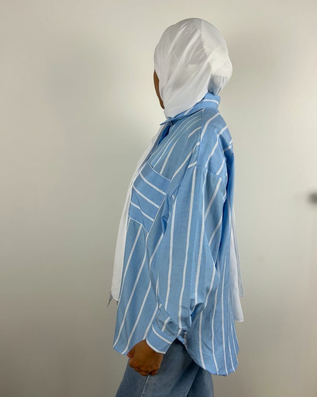 Chemise oversize rayée bleu ciel portée avec foulard blanc, vue de profil gauche