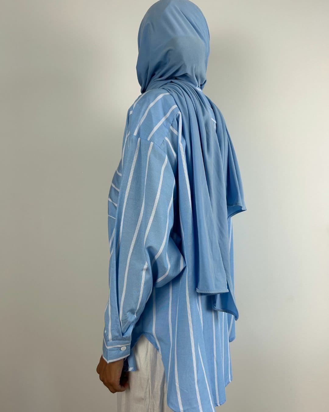 Chemise oversize rayée bleu ciel portée avec foulard bleu, vue de profil gauche