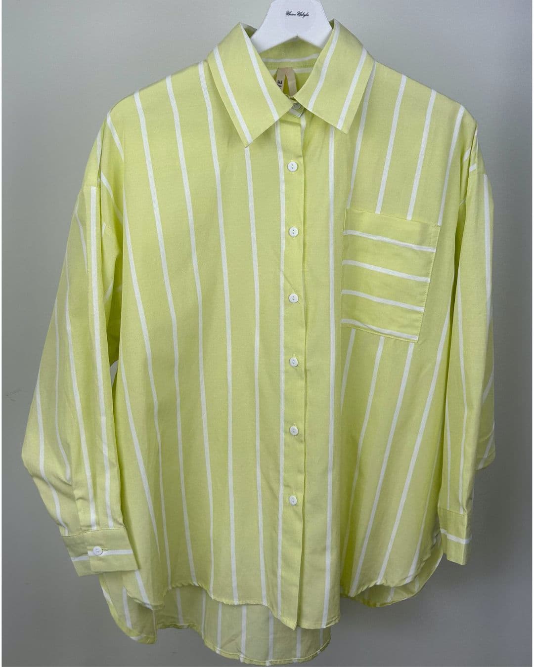 Chemise oversize rayée jaune pastel suspendue sur cintre, vue de face