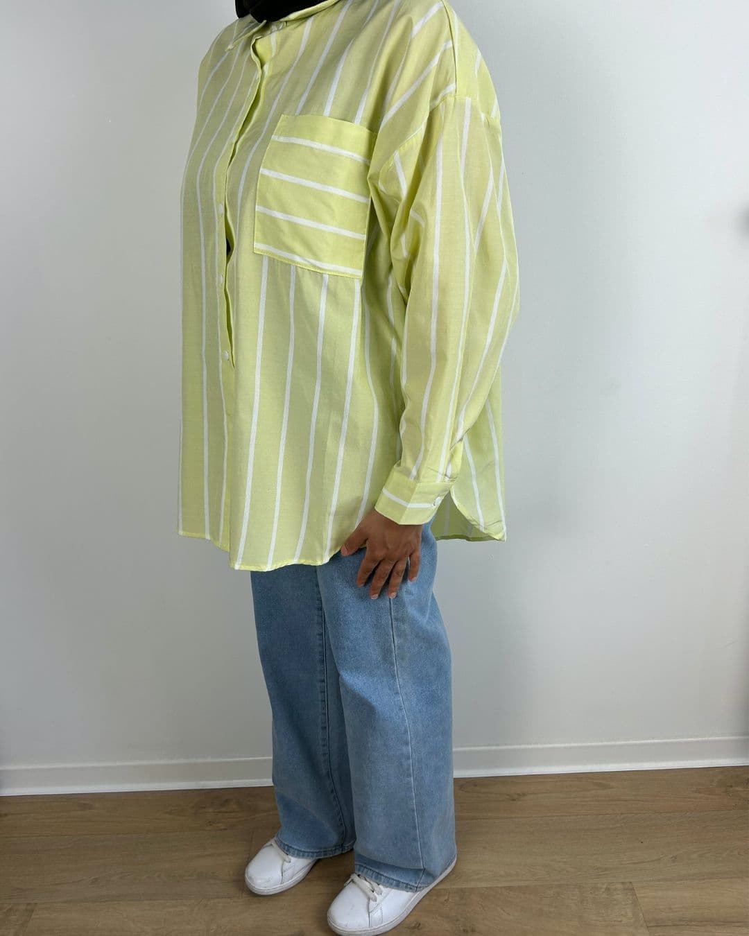 Femme portant une chemise rayée jaune pastel avec jean et baskets blanches