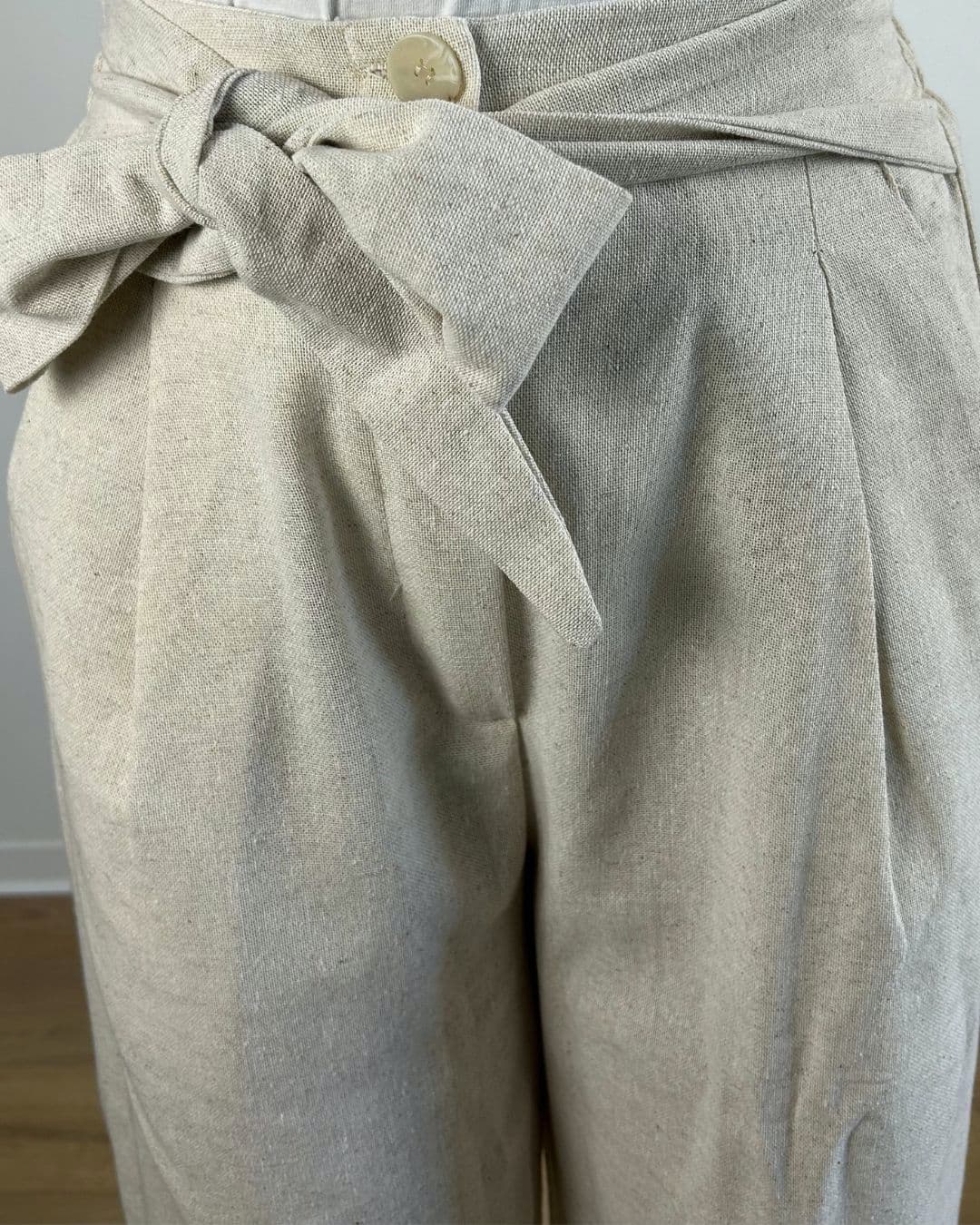 Gros plan sur la ceinture nouée d’un pantalon large en lin beige