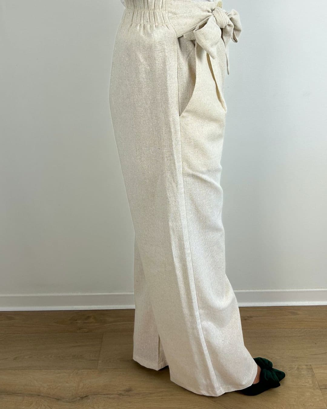 Vue latérale d’un pantalon en lin beige fluide avec ceinture nouée