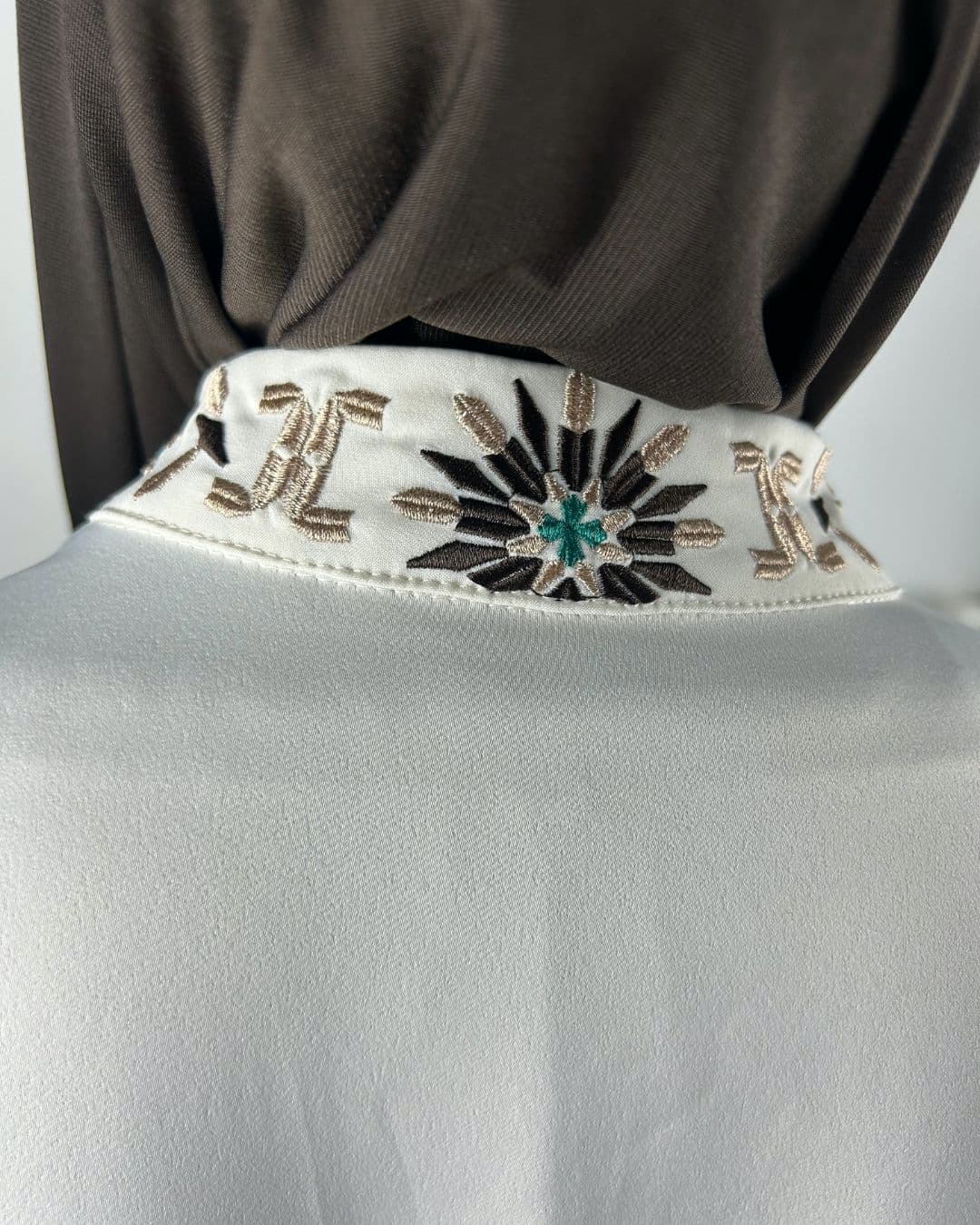 Gros plan sur la broderie florale au dos du col d’une robe satinée écrue