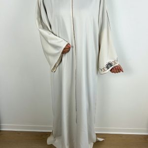 Zoom sur la broderie florale au poignet d’une robe satinée écrue