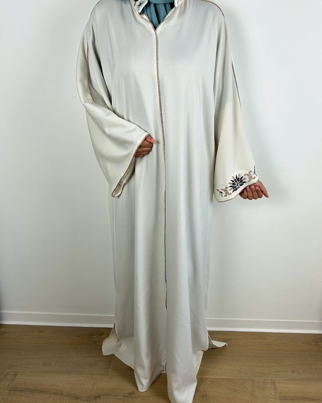 Zoom sur la broderie florale au poignet d’une robe satinée écrue