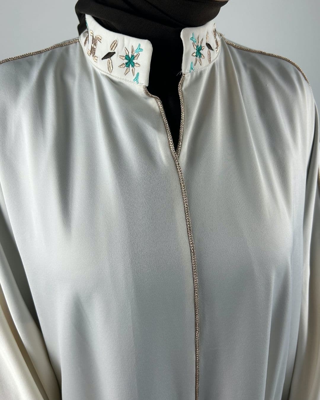 Femme portant une robe satinée écrue avec col brodé et liseré beige satiné, vue de face